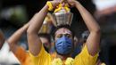 Umat Hindu mengenakan masker membawa teko susu dalam prosesi selama festival Thaipusam sebagai umat mematuhi prosedur operasi standar yang ketat karena pandemi COVID-19 di Gua Batu di pinggiran Kuala Lumpur, Malaysia, Selasa (18/1/2022). (AP Photo/ Vincent Thian)
