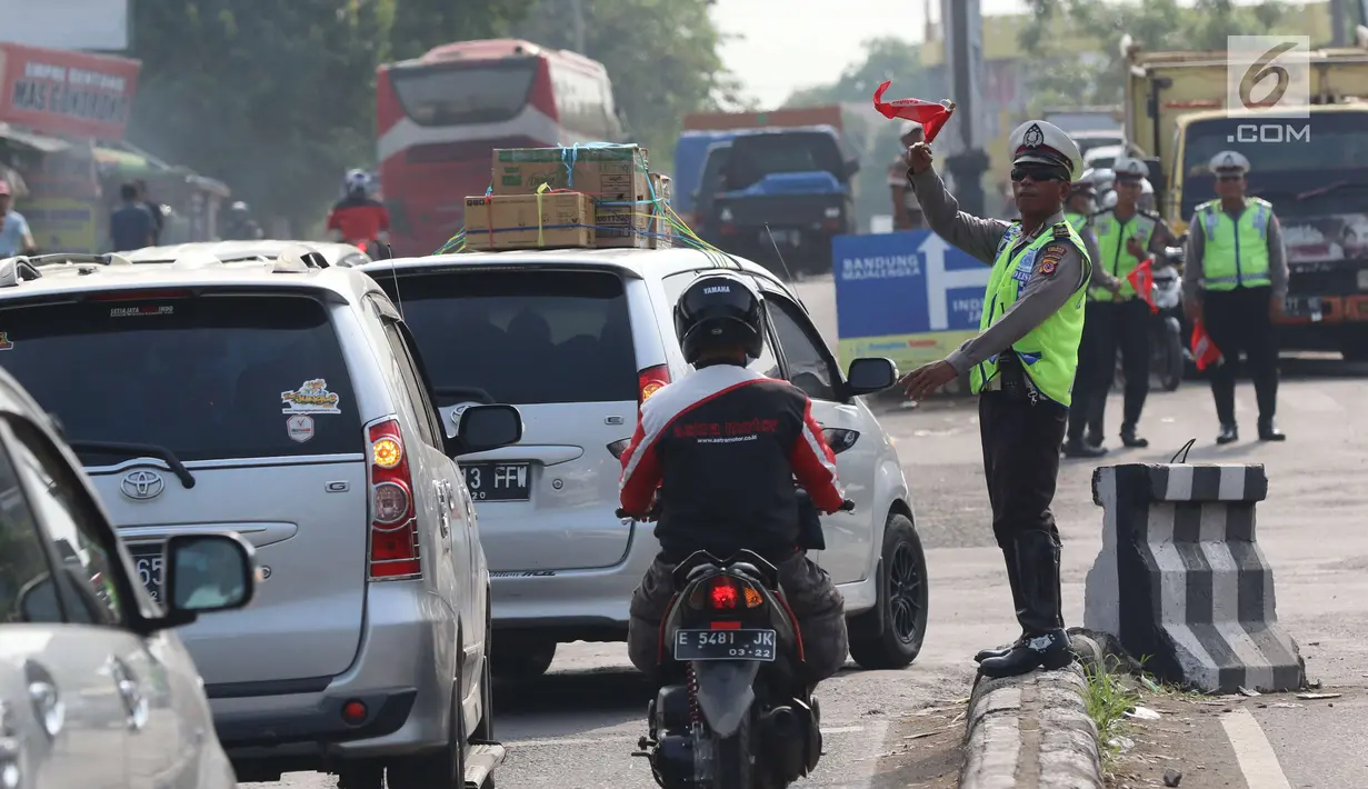 Aparat kepolisian Polres Cirebon Pantura mengatur lalu lintas kendaraan ke arah Tol Cipali, Indramayu, Jakarta dan ke arah Jawa Tengah di Pos Palimanan Cirebon, Jawa Barat, Jumat (30/6). (Liputan6.com/Helmi Afandi) 