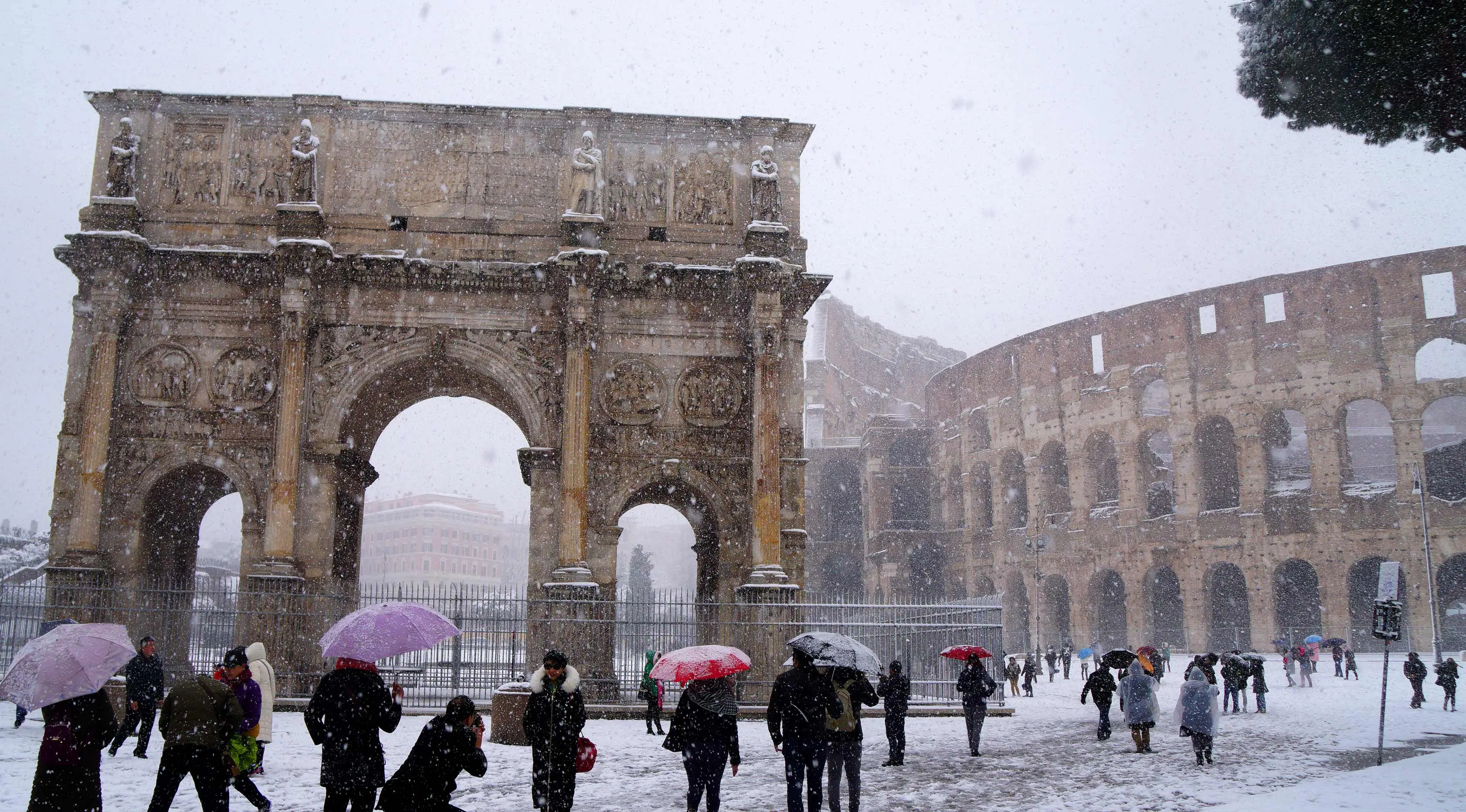 Sejumlah wisatawan mengabadikan Colosseum kuno saat hujan salju di Roma, Italia (26/2). (AFP Photo/Vicenzo Pinto)