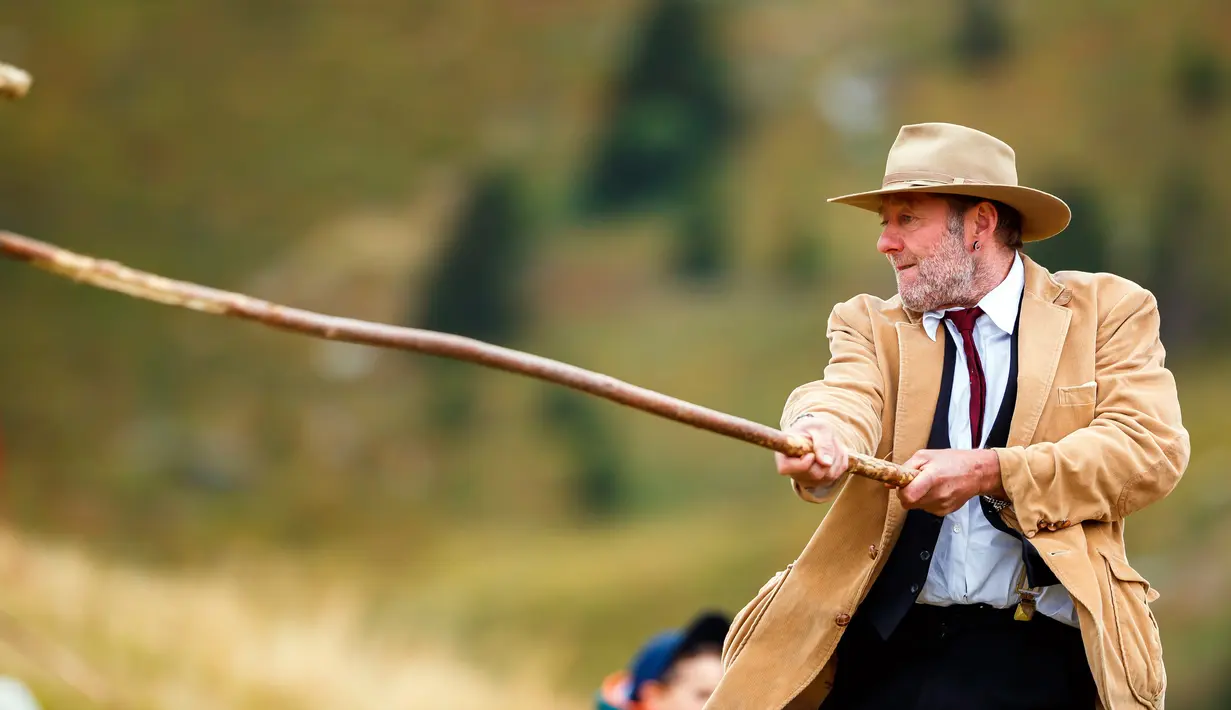 Seorang pria bermain permainan tradisional 'Gilihuesine' di resor pegunungan Bettmeralp, Swiss (16/9). Gilihuesine merupakan permainan campuran golf modern dan bisbol dan dimainkan sekali selama setahun di Bettmeralp. (Valentin Flauraud/Keystone via AP)