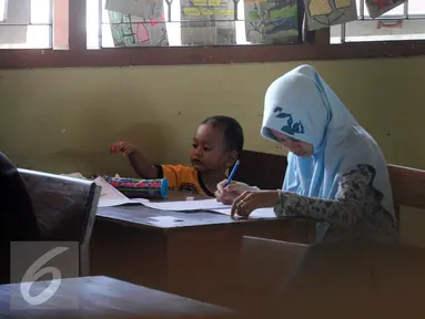 Seorang peserta membawa anaknya saat mengikuti ujian kesetaraan Paket C di SMPN 15 Yogyakarta, Senin (4/4). Sebanyak 447 peserta mengikuti ujian akhir untuk mendapatkan ijazah setingkat SMA. (Liputan6.com/Boy Harjanto)