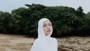 Berpose sendiri di pantai pasir putih, Aghnia Punjabi tampil simpel dengan atasan dan celana putih, dan hijab putih polos. [Foto: Instagram/emyaghnia]