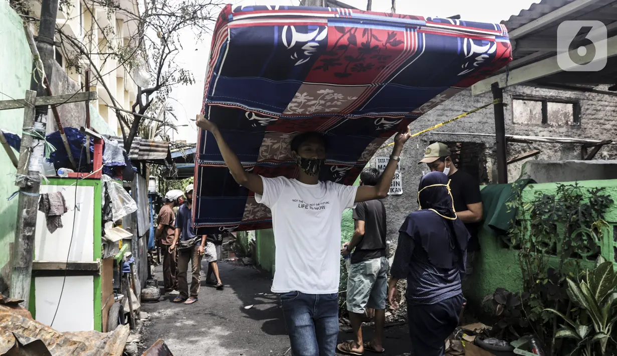 Warga membawa kasur sisa kebakaran di permukiman padat Kelurahan Bali Mester, Jatinegara, Jakarta, Selasa (8/9/2020). Kebakaran di permukiman padat itu melalap 11 rumah tinggal warga serta satu unit bengkel dan mengakibatkan 60 orang mengungsi. (Liputan6.com/Johan Tallo)