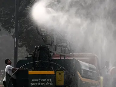 Sebuah kendaraan dari Departemen Pekerjaan Umum (PWD) menyemprotkan air dengan menggunakan penyemprot anti-kabut asap untuk mengurangi polusi udara di New Delhi, India pada 7 November 2024. (Arun SANKAR/AFP)