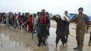 Tentara membagikan makanan dan barang-barang lainnya kepada orang-orang terlantar di sebuah kamp bantuan di daerah yang dilanda banjir di distrik Jamshoro, di Pakistan selatan, Rabu (24/8/2022). Hujan deras telah memicu banjir bandang dan mendatangkan malapetaka di banyak tempat. (AP Photo/Pervez Masih)