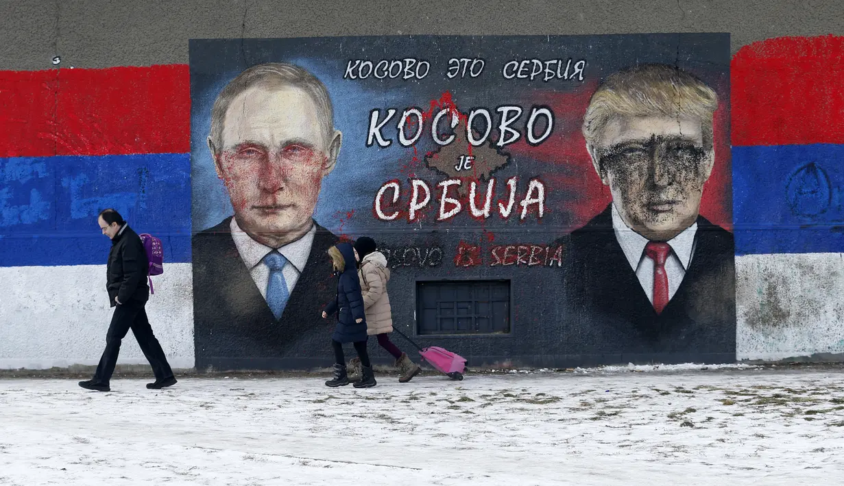 Sejumlah orang melintas di depan grafiti bergambar Donald Trump dan Vladimir Putin yang dirusak dengan cat di Belgrade, Serbia, Jumat (20/1). Diduga pelaku pengrusakan adalah mereka yang tak suka Trump menjadi Presiden AS. (AP Photo / Darko Vojinovic) 