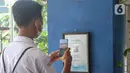 Siswa memindai QR Code dengan aplikasi PeduliLindungi saat hari pertama pembelajaran tatap muka di SMP 26 Depok, Depok, Jawa Barat, Senin (24/1/2022). Pemerintah Kota Depok mulai menggelar Pembelajaran Tatap Muka (PTM) secara penuh atau 100 persen mulai hari ini. (Liputan6.com/Herman Zakharia)