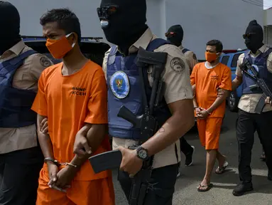 Petugas Badan Narkotika Nasional Indonesia (BNN) mengawal dua pria lokal yang diduga menyelundupkan sabu pada konferensi pers di Banda Aceh (13/10/2020). (AFP Photo/Chaideer Mahyuddin)