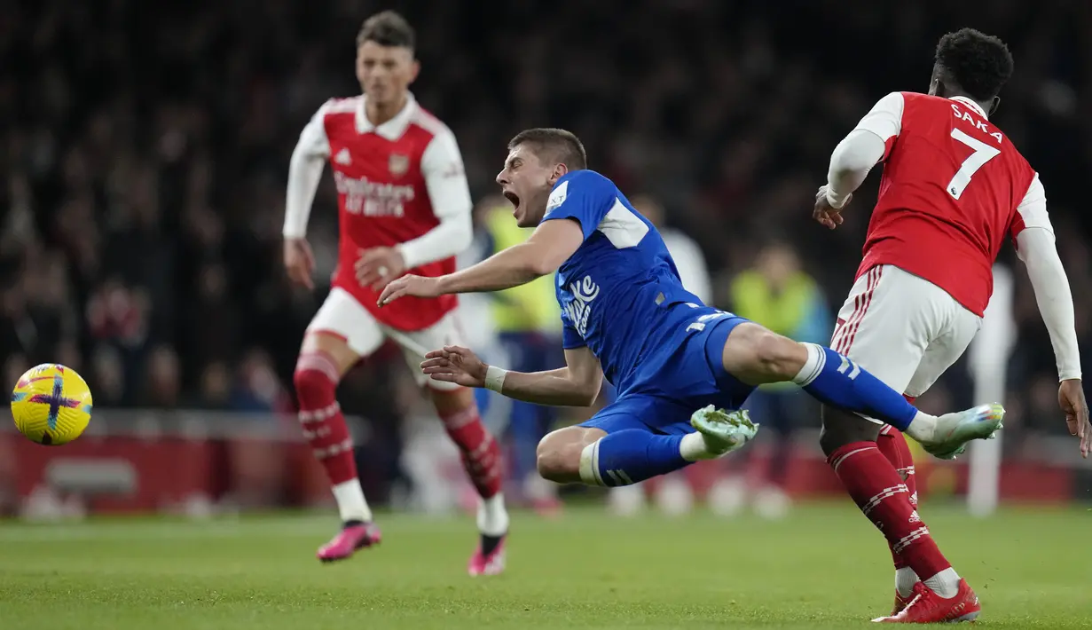 Pemain Everton, Vitaliy Mykolenko (tengah) berebut bola dengan pemain Arsenal, Bukayo Saka pada laga lanjutan Liga Inggris 2022/2023 melawan Arsenal yang berlangsung di Emirates Stadium, London, Kamis (02/03/2023) WIB. Arsenal berhasil menang telak dengan skor 4-0. (AP Photo/Kirsty Wigglesworth)