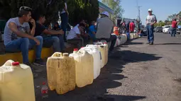 Warga antre menggunakan jerigen di tengah kelangkaan BBM di sebuah SPBU di Morelia, Meksiko, Selasa (8/1). Kelangkaan BBM akibat terjadinya pencurian dari jaringan pipa dan dari internal Pemex, perusahaan minyak milik negara. (ENRIQUE CASTRO/AFP)