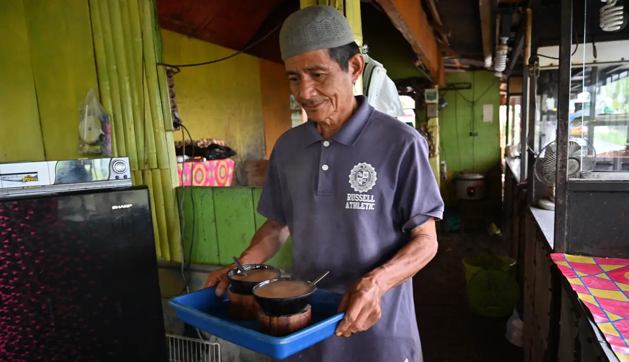 Seorang pria membawa kopi Kawa Daun di sebuah kafe tradisional di Tabek, Sumatera Barat (29/11).  Keunikan kopi di daerah ini adalah minuman yang mengekstrak rasa dari daun tanaman daripada kacangnya. (AFP Photo/Adek Berry)