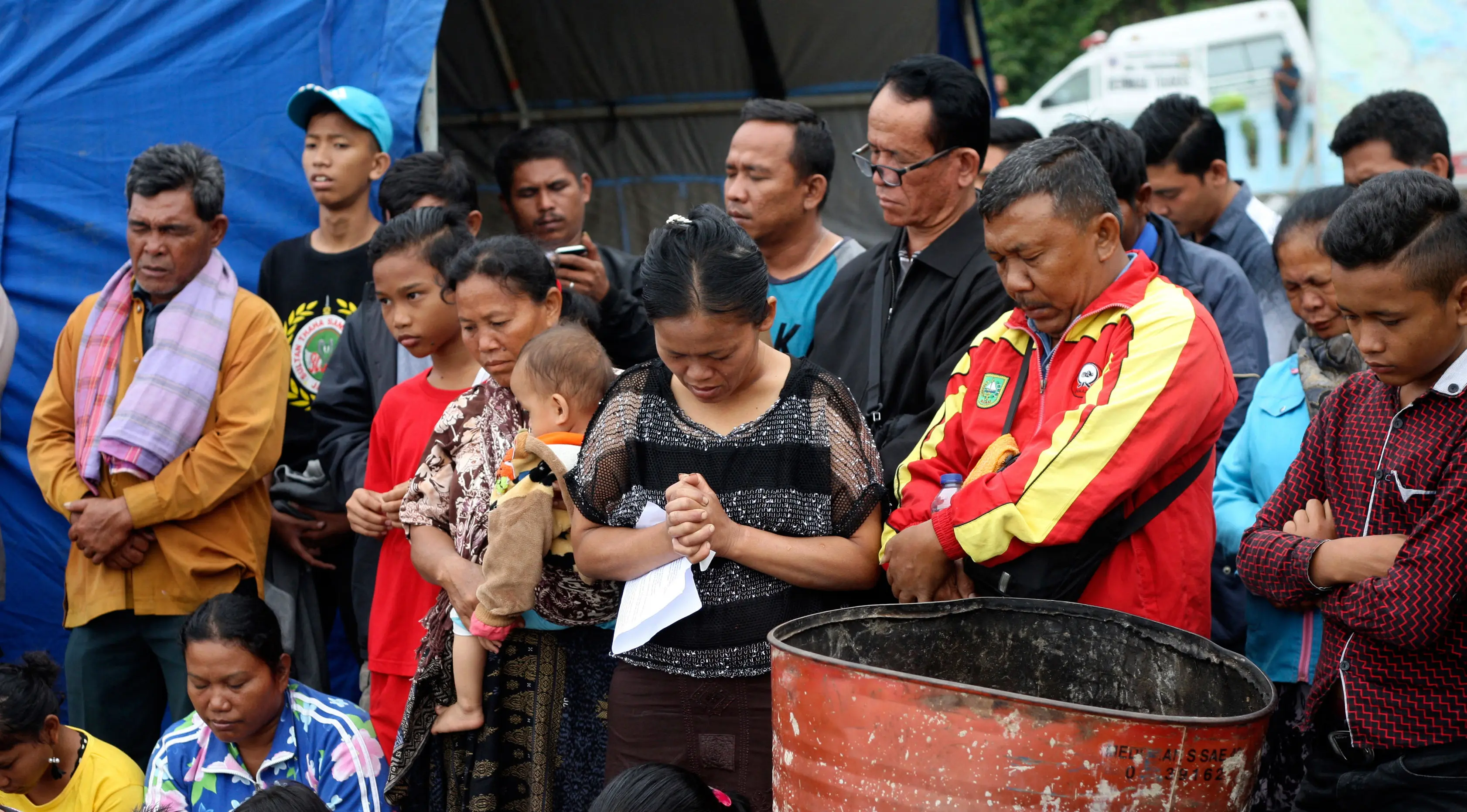 Keluarga dan warga berdoa untuk penumpang yang hilang dari kecelakaan KM Sinar Bangun di Danau Toba di Pelabuhan Tigaras, Sumatra Utara, Indonesia (21/6). Kapal tersebut membawa ratusan penumpang. (AP Photo/Binsar Bakkara)