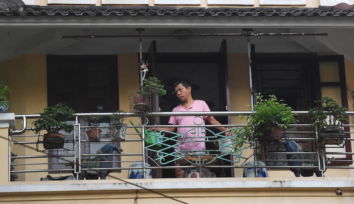 Gambar pada 3 September 2021 menunjukkan seorang pria menyirami tanaman di balkon rumahnya di Hanoi, Vietnam, selama lockdown Covid-19. Menghadap ke jalan yang sepi, balkon kecil mereka menjadi saksi bisu terkait aktivitas yang dilakukan oleh masing-masing keluarga. (Nhac NGUYEN/AFP)