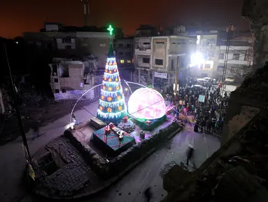 Suasana perayaan malam Natal di kawasan Al-Hamidiyah yang dikelilingi reruntuhan bangunan kota tua Homs, Suriah, (24/12). (REUTERS/Omar Sanadiki)
