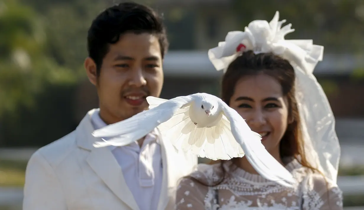 Sepasang pengantin melepaskan burung merpati saat upacara pernikahan di provinsi Ratchaburi, Thailand, Sabtu (13/2). Upacara pernikahan tersebut diikuti oleh empat pasang pengantin untuk menyambut Hari Valentine. (REUTERS/Athit Perawongmetha)
