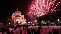 Orang-orang menyaksikan kembang api meledak di atas Kuil St. Sava di Beograd, Serbia, Jumat (14/1/2022). Umat Kristen Ortodoks di Serbia merayakan Tahun Baru pada 14 Januari, menurut kalender Julian. (AP Photo/Darko Vojinovic)