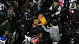Pemudik bersepeda motor dengan membawa anak antre menunggu giliran masuk ke kapal "Roll on-Roll off" (RoRo) di Pelabuhan Merak, Banten, Kamis (28/4/2022). Puncak arus mudik H-3 lebaran di Pelabuhan Merak sudah dipenuhi oleh pemudik. Tampak, pemudik yang membawa anak kecil serta barang bawaan yang diikat di belakang motor. (Liputan6.com/Angga Yuniar)