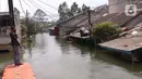 Warga melintasi jembatan apung saat banjir melanda perumahan Periuk Damai, Tangerang, Banten, Selasa (22/2/2021). Banjir setinggi 2,5 meter tersebut sudah terjadi selama 4 hari. (Liputan6.com/Angga Yuniar)