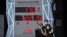 Orang-orang yang memakai masker untuk melindungi diri dari COVID-19 berpose di depan layar yang menunjukkan jam hitung mundur ke Olimpiade Musim Dingin 2022 di Beijing (18/8/2021).  Pejabat tinggi Beijing menegaskan kembali perlunya anti-pencegahan yang ketat. (AP Photo/Mark Schiefelbein)