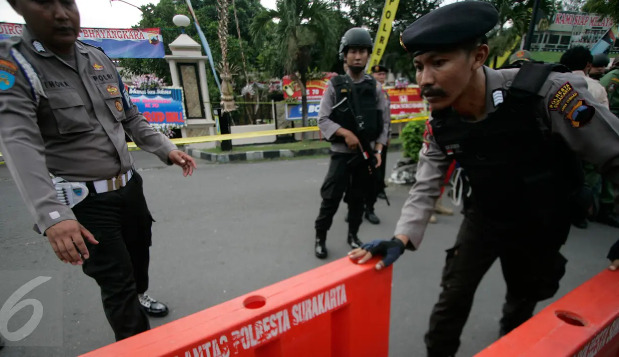 Petugas kepolisian bersiap memasang garis polisi di lokasi bom bunuh diri di Mapolresta Solo, Jawa Tengah, Selasa (5/7). Garis polisi itu dipasang mulai dari sisi barat jalan Adi Sucipto menuju sisi timur Jalan KS Tubun. (Liputan6.com/Boy Harjanto)