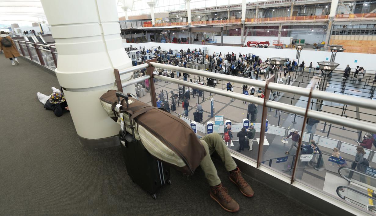 Penumpang tidur di tengah barang bawaannya di atas pos pemeriksaan Bandara Internasional Denver di Denver, AS, Senin (3/1/2022). Badai musim dingin ditambah pandemi membuat frustrasi pelancong yang penerbangan pulang dari liburannya dibatalkan atau ditunda di awal tahun. (AP Photo/David Zalubowski)
