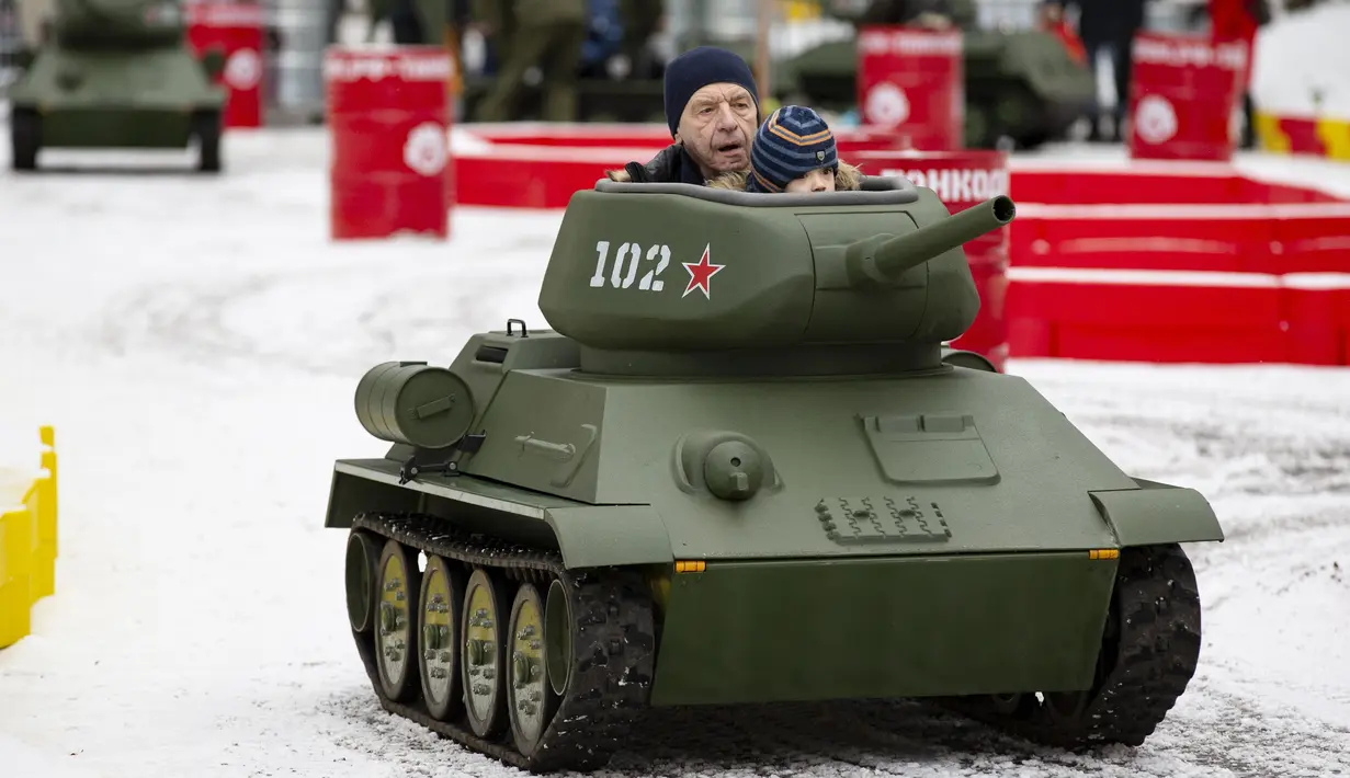 Seorang anak ditemani seorang pria mengendarai model tank T-34 era Soviet yang legendaris di objek wisata petualangan anak-anak Tankodrom di taman Sokolniki di Moskow, Rusia (6/1/2020). Perlombaan dengan menggunakan tank ini dikenai biaya sekitar US $ 6,5 AS. (AP Photo/Alexander Zemlianichenko)