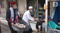 Sejumlah warga tengah membagikan nasi bungkus kepada warga yang terdampak Covid-19 di di RW 03, Kelurahan Gandasari, Kecamatan Jatiuwung, Kota Tangerang, Jumat (11/6/2021).  (Liputan6.com/Angga Yuniar)