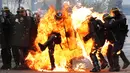 Seorang perwira polisi Prancis terbakar dalam bentrokan dengan pengunjuk rasa perayaan May Day di Paris, Senin (1/5). Satu polisi mengalami luka bakar serius dan dua lainnya luka-luka dalam bentrokan yang melibatkan bom molotov. (Zakaria ABDELKAFI/AFP)