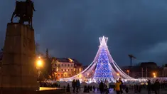 Orang-orang berjalan di dekat pohon Natal raksasa yang menerangi Alun-Alun Katedral di Vilnius, Lithuania, Minggu (1/12/2019). Secara tradisi, pohon Natal Vilnius biasanya berupa rangka logam yang ditutupi dengan dekorasi dan cabang-cabang pohon dari hutan. (AP/Mindaugas Kulbis)