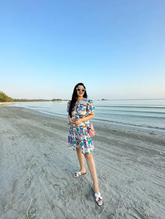 OOTD simpel Fitri Carlina liburan di pantai. Ia mengenakan dress berkerah lengan pendek bermotif ramai, simpel memadukannya dengan sandal dan sunglasses dengan frame putih. [Foto: Instagram/fitricarlina]