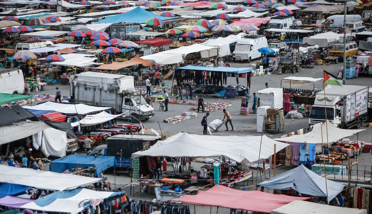 Suasana aktivitas pasar yang kembali ramai setelah pelonggaran karantina wilayah di kamp pengungsi Nuseirat di Jalur Gaza tengah, Senin (13/7/2020). Aktivitas perekonomian seperti kegiatan jual beli di pasar tradisional mulai kembali dibuka. (AFP/Mohammed Abed)