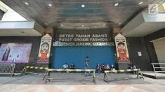 Sejumlah orang duduk di depan pintu masuk pasar Blok A Tanah Abang, Jakarta, yang tutup pada Kamis (23/5/2019). Pengelola Pasar Tanah Abang menutup sementara aktivitas perdagangan demi mengantisipasi dampak kericuhan Jakarta dalam beberapa hari ini. (Liputan6.com/Herman Zakharia)
