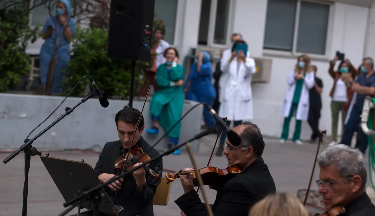 Para anggota ERT (Hellenic Broadcasting Corporation) Modern Music Orchestra memainkan musik di halaman Rumah Sakit Umum Evaggelismos di Athena, Yunani (20/4/2020). Konser digelar oleh ERT Modern Music Orchestra untuk menghormati staf medis dalam perjuangan melawan COVID-19. (Xinhua/Marios Lolos)