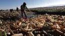 Seorang petugas polisi mengais sampah di Sungai Tagaret yang tercemar yang mengalir ke Danau Uru Uru, dekat Oruro, Bolivia, Rabu (7/4/2021). Operasi pembersihan dimulai untuk mengembalikan danau ke keindahan alamnya yang telah dibanjiri sampah plastik dan limbah buatan manusia lainnya (AP/Juan Kari)