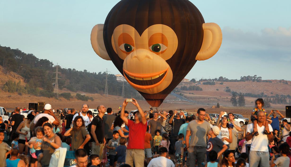 Sejumlah pengunjung menyaksikan Festival Balon Udara Gilboa di dekat Kibbutz Ein Harod, Lembah Jizreel, Israel (4/8). Acara ini juga dimeriahkan dengan pertunjukan paragliders, paramotor dan karya para seniman udara. (AFP Photo/Manahem Kahana)