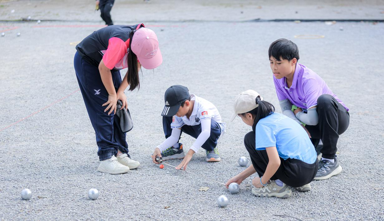Beberapa anak memainkan olahraga Petanque di Lapangan Latih Dua Kompleks 700th Anniversary of Chiang Mai Stadium, Thailand, Kamis (11/12/2025). Petanque merupakan salah satu olahraga favorit bagi masyarakat Thailand. (Bola.com/Bagaskara Lazuardi)