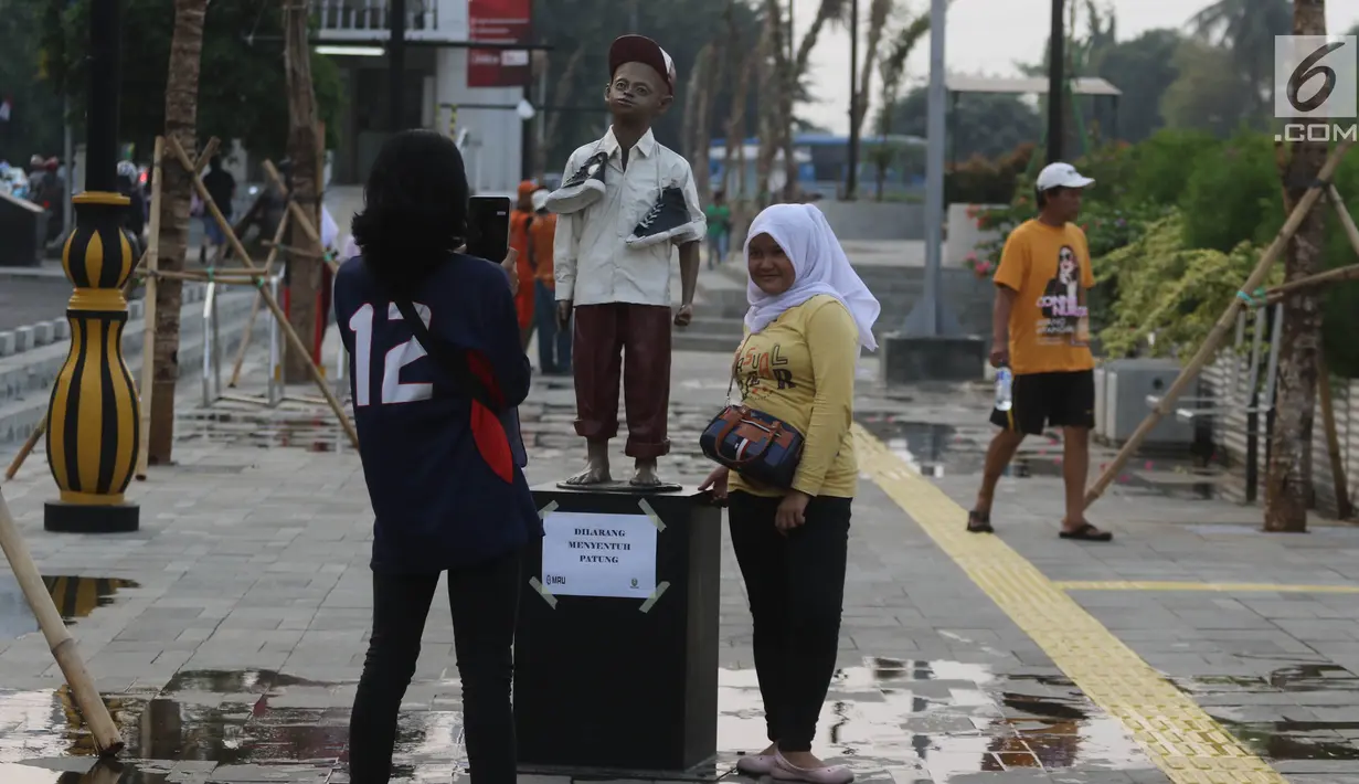 Warga berfoto-foto di kawasan pedestrian Kali Besar, Kota Tua, Jakarta, Rabu (11/7). Masyarakat sudah bisa mengakses area yang proyek revitalisasinya telah berlangsung sejak 2017 lalu, dan menghabiskan anggaran Rp 260 miliar. (Liputan6.com/Arya Manggala)