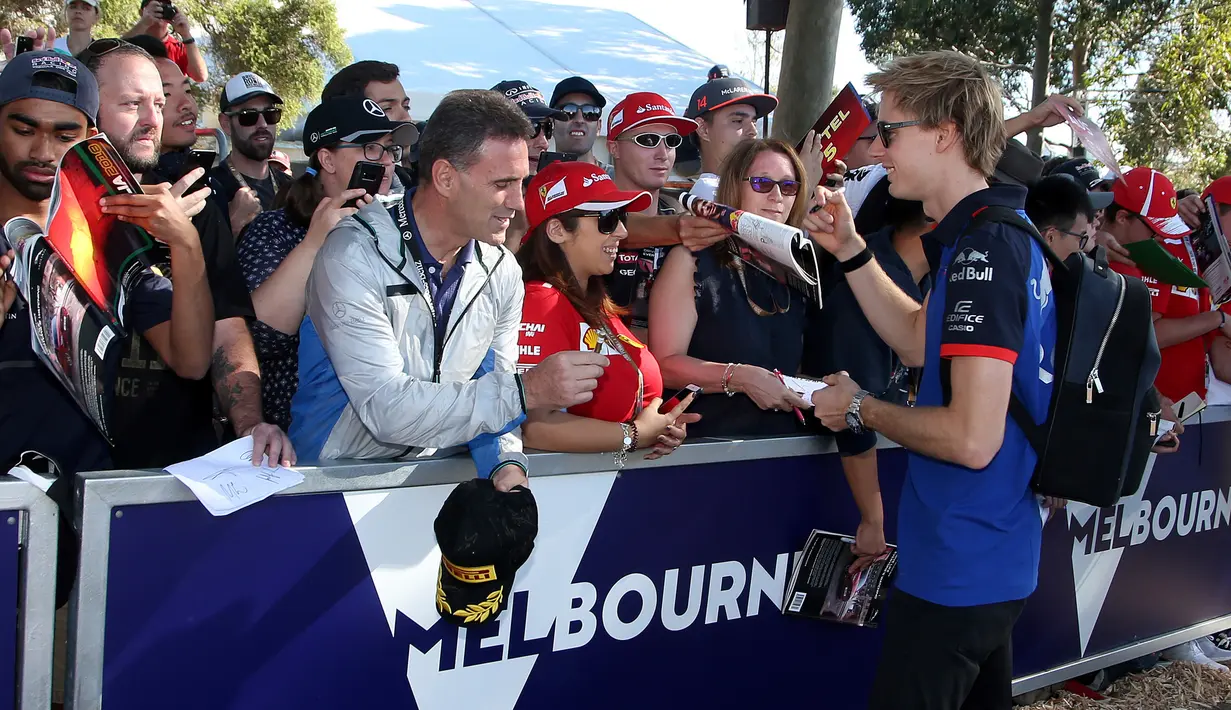 Pembalap Toro Rosso, Brandon Hartley memberikan tanda tangan kepada fans sesaat sebelum latihan bebas Formula 1 (F1) GP Australia di Melbourne, Jumat (23/3). Balapan F1 GP Australia 2018 sendiri akan bergulir pada Minggu, 25 Maret besok. (AP/Rick Rycroft)