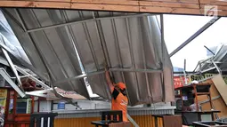 Petugas PPSU mengevakuasi atap kios Rasuna Garden Food Street usai roboh akibat angin kencang di kawasan Kuningan, Jakarta, Senin (10/12). Kios Rasuna Garden Food Street mengalami kerusakan parah. (Merdeka.com/Iqbal Nugroho)