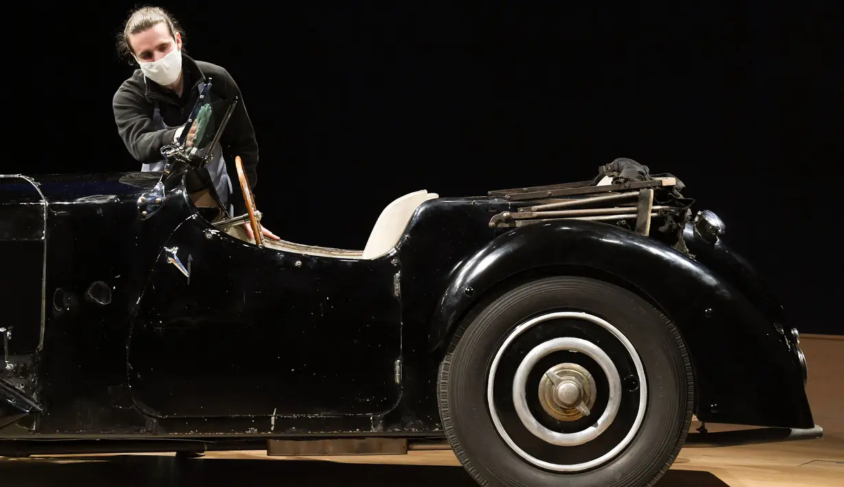 Staf berpose dengan Bugatti Type 57S 1937, salah satu mobil pra-perang paling diinginkan di dunia, di luar rumah lelang Bonhams,  London, Selasa (16/2/2021). Bugatti yang tidak pernah terlihat selama 50 tahun ini merupakan salah satu dari 42 contoh varian 57S yang diproduksi (DANIEL LEAL-OLIVAS/AFP)