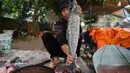 Seorang pria menyiapkan ikan gurame untuk dimasak di pot tanah menggunakan kayu bakar di provinsi Ha Nam, Vietnam, Selasa (21/1/2020). Makanan lezat populer untuk Tahun Baru Imlek atau Tet di utara Vietnam itu dijual dengan masing-masing pot sekitar Rp 25ribu hingga Rp 80ribu. (Nhac NGUYEN / AFP)