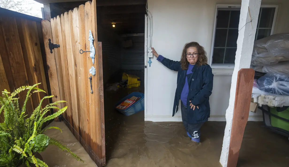 Teresa Fuentes melihat barang-barangnya rusak akibat banjir di rumahnya di College Road di Watsonville, California, Jumat, 10 Maret 2023. Evakuasi diperintahkan di dekat Watsonville di mana air sungai meluap dan memenuhi jalan raya dengan air setinggi beberapa kaki, mengancam puluhan rumah dengan banjir. (AP Photo/Nic Coury)