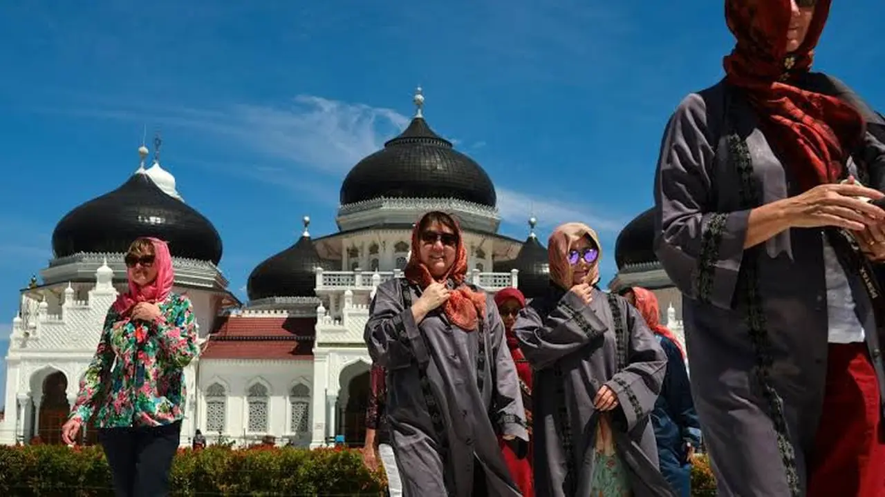 Turis asing mengenakan jilbab saat mengunjungi Masjid Agung Baiturrahman di Banda Aceh, Aceh pada 6 Agustus 2019. Selain sebagai tempat ibadah, Masjid Baiturahman juga menjadi tempat wisata bagi turis lokal dan mancanegara. (CHAIDEER MAHYUDDIN / AFP)