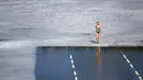 Seorang perempuan bersiap berlaga di kompetisi renang musim dingin di lubang es sepanjang 25 meter di sebuah danau dekat Vilnius, Lithuania, Sabtu (6/3/2021).  Suhu air saat itu 3 derajat Celcius, sedangkan udaranya -3 derajat Celsius. (AP Photo/Mindaugas Kulbis)