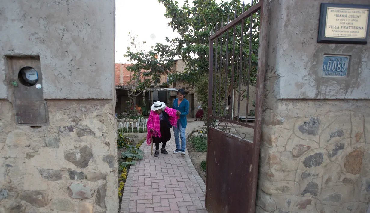 Cucu buyut Rosa Lucas membantu sang bibi, Julia Flores Colque yang berusia 117 tahun pergi berjalan-jalan di luar rumahnya di Sacaba, Bolivia, 23 Agustus 2018. Akte kelahiran Julia tidak tercatat di Bolivia sampai 1940. (AP/Juan Karita)