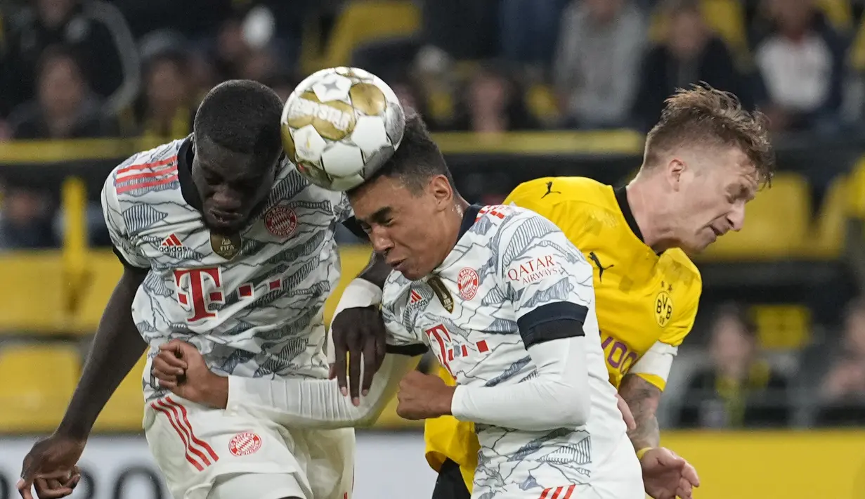 Gelandang Borussia Dortmund, Marco Reus berebut bola dengan dua pemain Bayern Munchen, Dayot Upamecano dan Jamal Musiala selama pertandingan final Piala Super Jerman di Signal Iduna Park, Jerman, Rabu (18/8/2021). Munchen menang atas Dortmund dengan skor 3-1. (AP Photo/Martin Meissner)