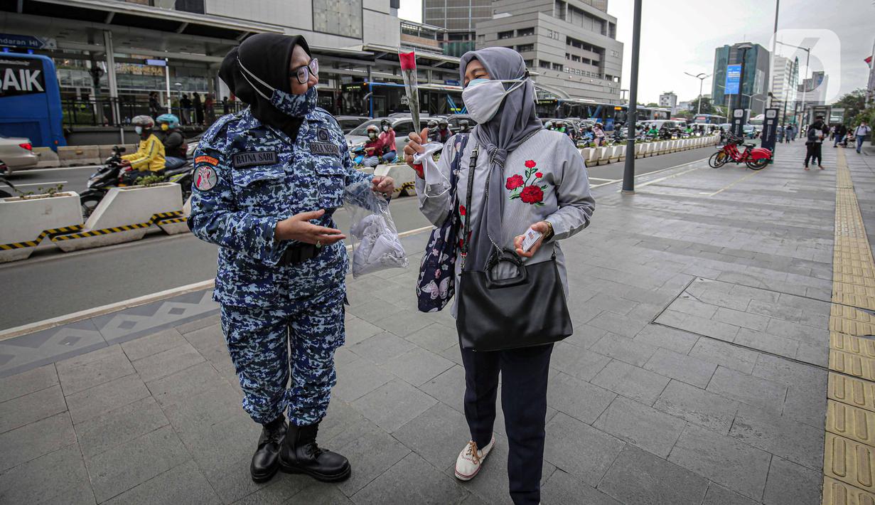 Perserta yang tergabung dalam Forum Kader Bela Negara DKI Jakarta membagikan bunga dan masker kepada pejalan kaki di Jalan Thamrin, Jakarta, Rabu (22/12/2021). Aksi tersebut merupakan bentuk apresiasi terhadap kaum perempuan terutama pada peringatan Hari Ibu. (Liputan6.com/Faizal Fanani)