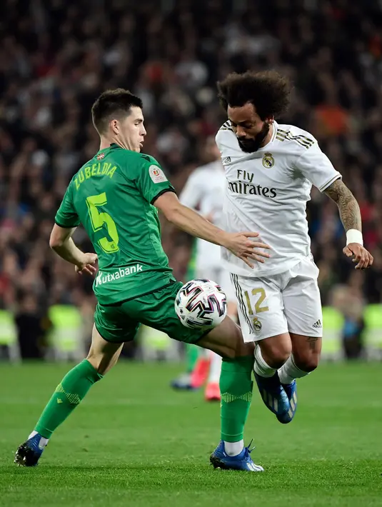 Gelandang Real Sociedad, Igor Zubeldia (kiri) berebut bola dengan bek Real Madrid, Marcelo pada laga perempat final Copa del Rey di Santiago Bernabeu, Kamis (6/2/2020). Real Madrid gagal melaju ke semifinal Copa del Rey setelah dibungkam Real Sociedad dengan skor 3-4. (JAVIER SORIANO/AFP)