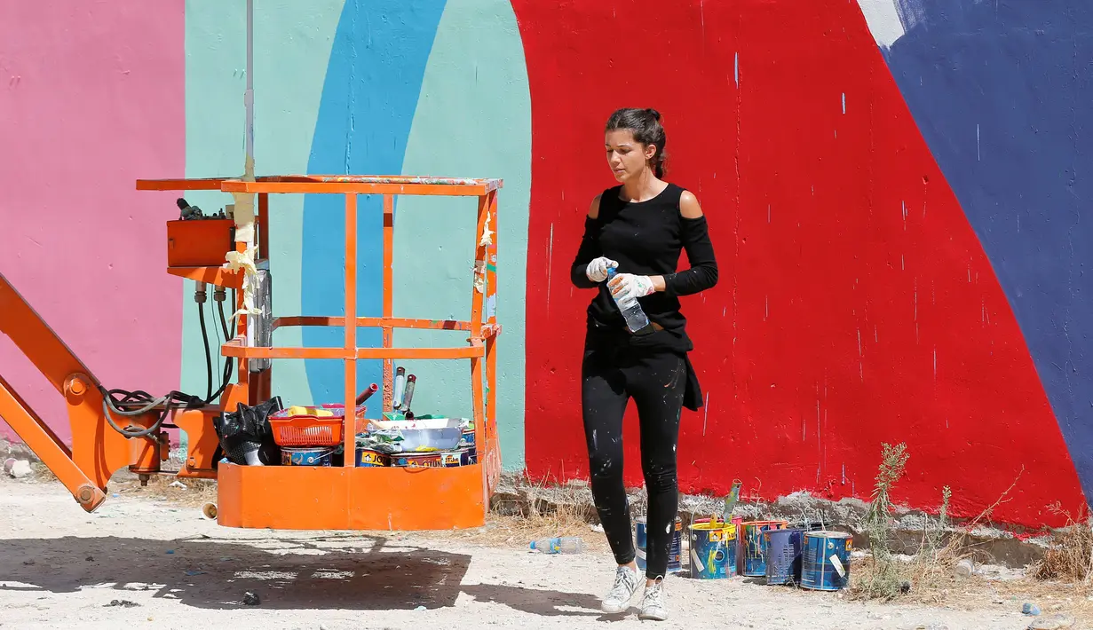 Tarsila Schubert beristirahat sebelum melanjutkan membuat mural di Museum Seni Terbuka, Kota Amman, Yordania, Kamis (29/9). Seniman cantik ini membuat mural untuk mengampanyekan pentingnya pemberdayaan perempuan. (REUTERS/Muhammad Hamed)