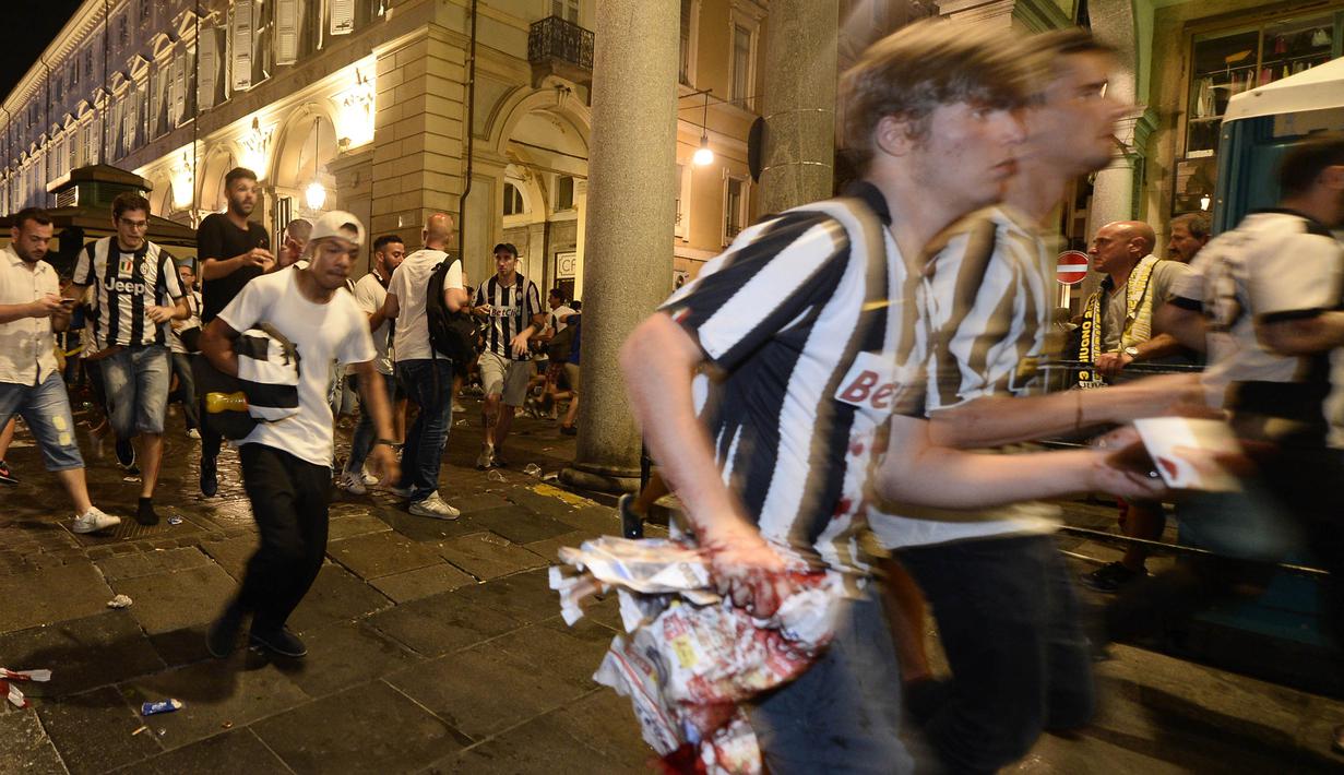 Para supporter tampak berlari panik usai terjadi ledakan saat nonton bareng final Liga Champions di Piazza San Carlo, Turin, Sabtu (3/6/2017). Acara nobar dipadati sekitar 20.000 supporter Juventus. (AFP/Massimo Pinca)
